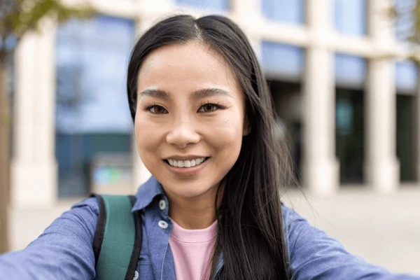 smiling asian woman takes selfie
