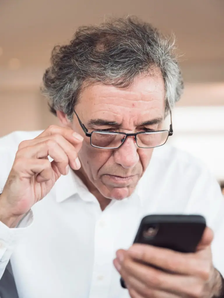 old man checking his phone with reading glasses