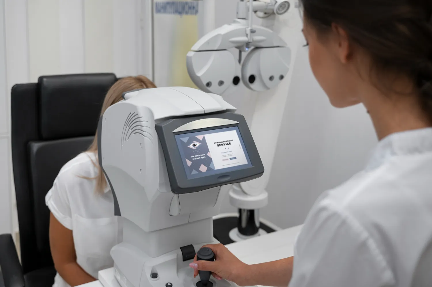 Optometrist performing an eye exam on a patient using an autorefractor machine.