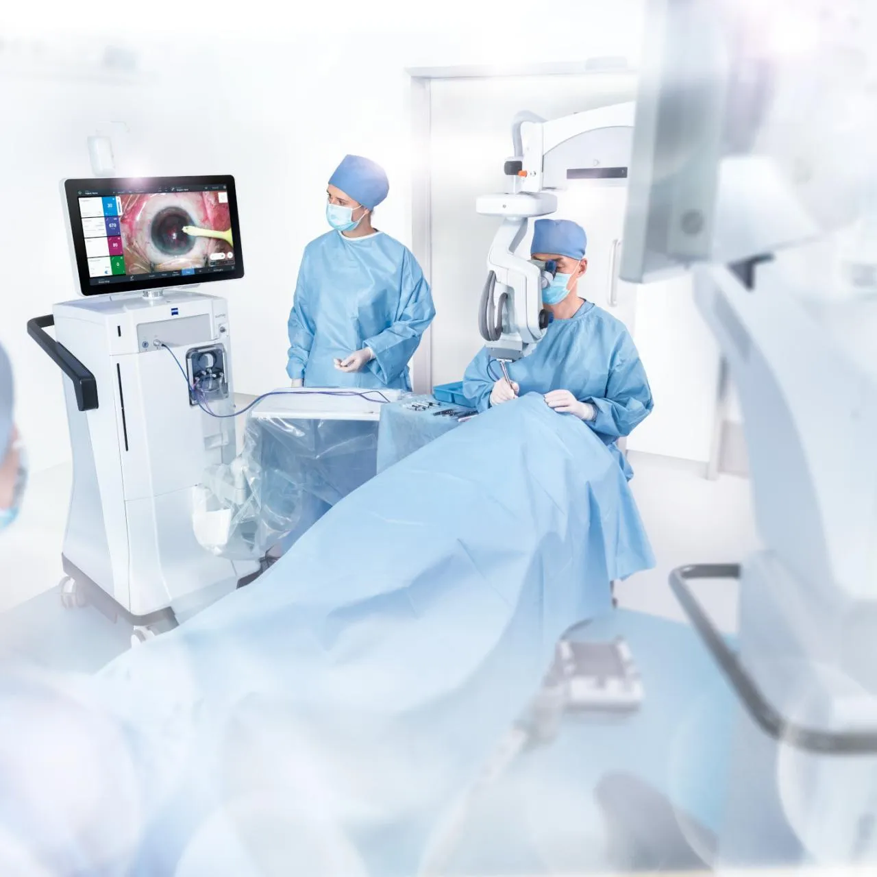 Surgeons in an operating room perform eye surgery with advanced medical equipment. A large monitor displays a magnified view of an eye.